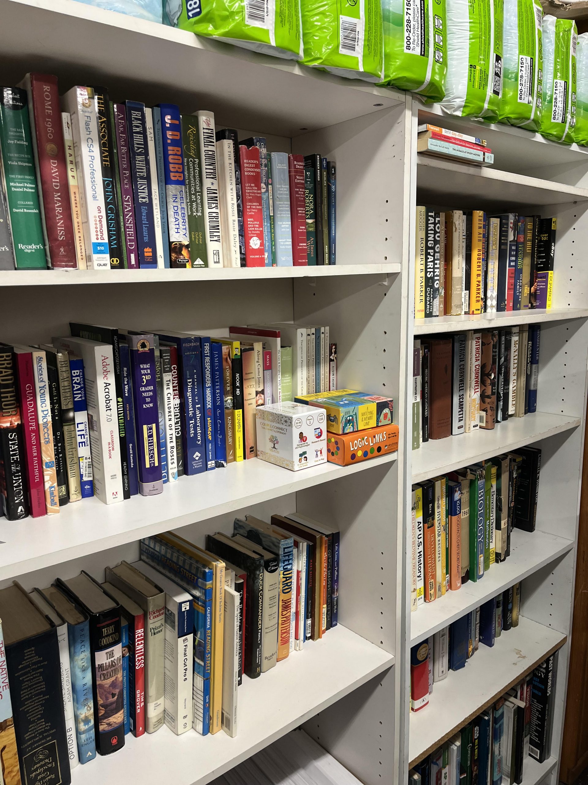 White bookshelves filled with a variety of books line a wall