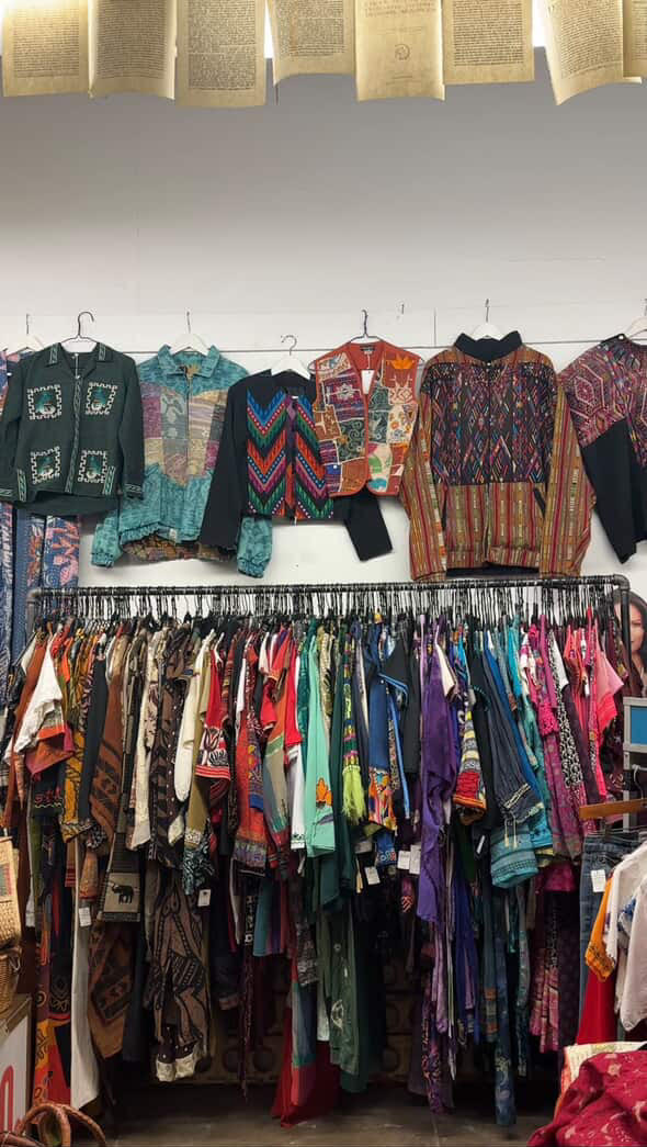 Jackets and dresses hang on racks and a wall display