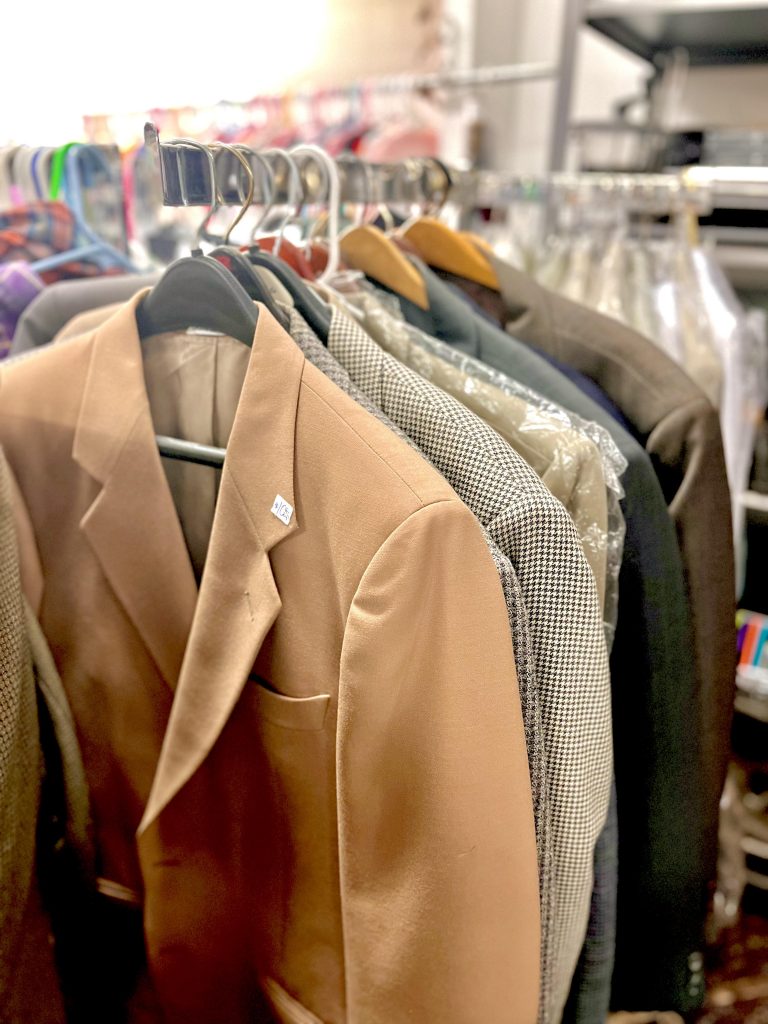 A rack of coats, a brown jacket in the front